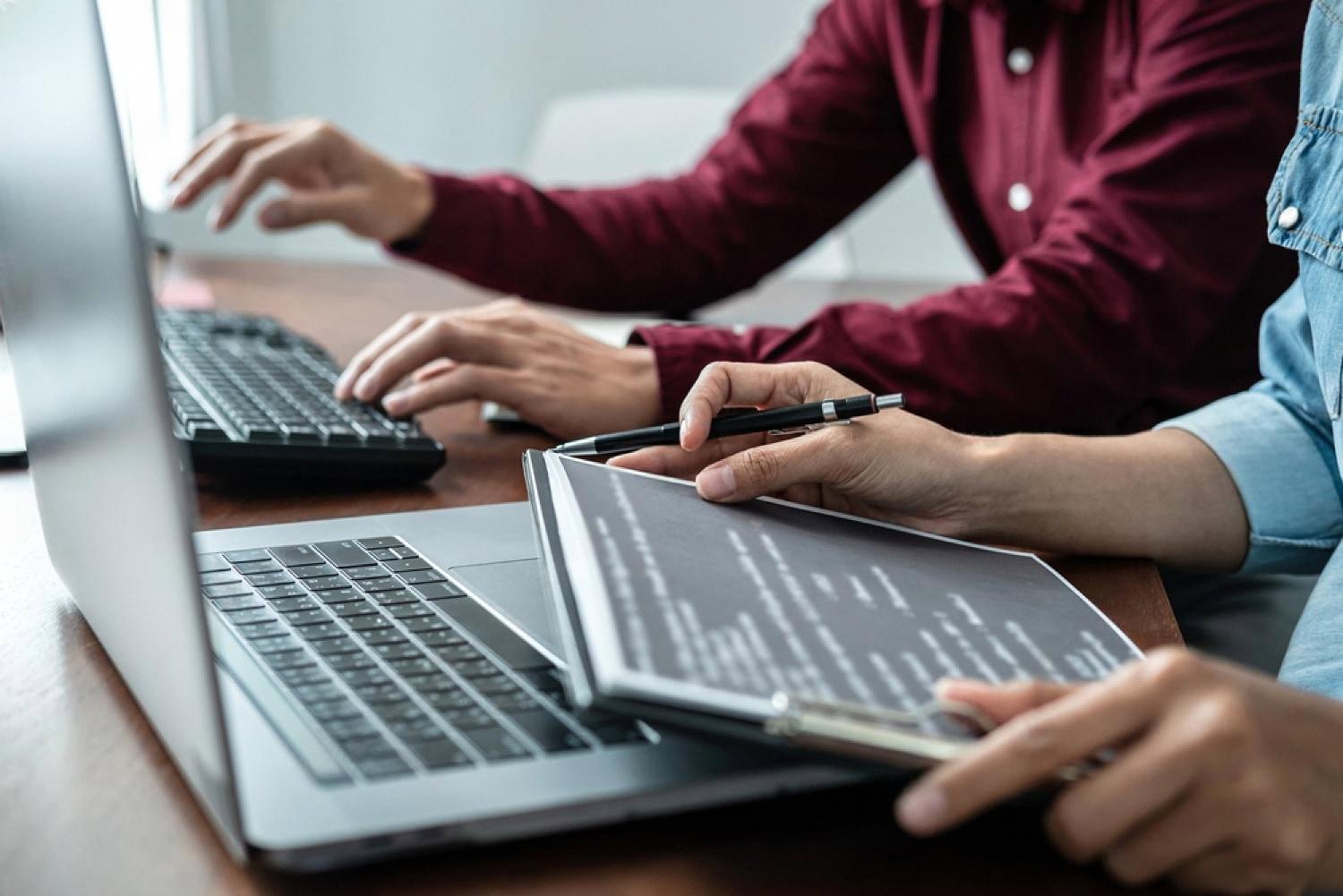 Two colleagues reviewing a printed security policy next to a laptop in a Dubai office